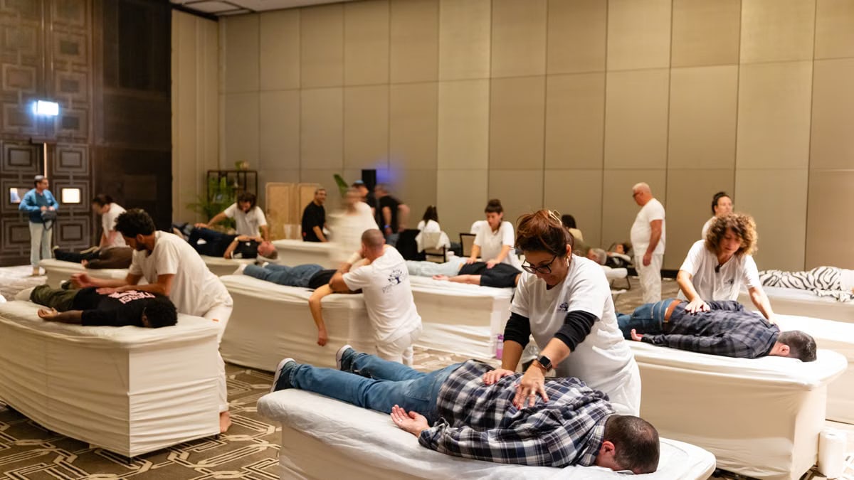 Group of therapists providing massages at an indoor wellness session.